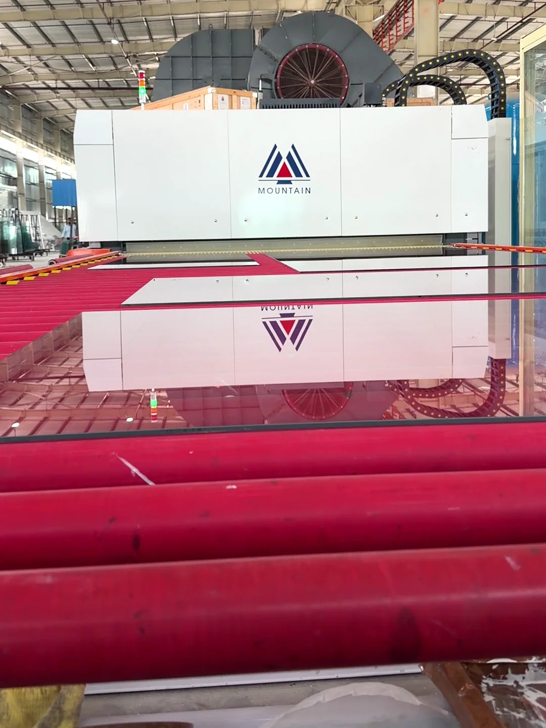 A sheet on the rollers before ARG's new toughening furnace, the furnace reflected in it
